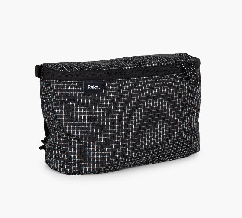 Black travel pouch with white grid pattern, zip closure and visible Pakt. label