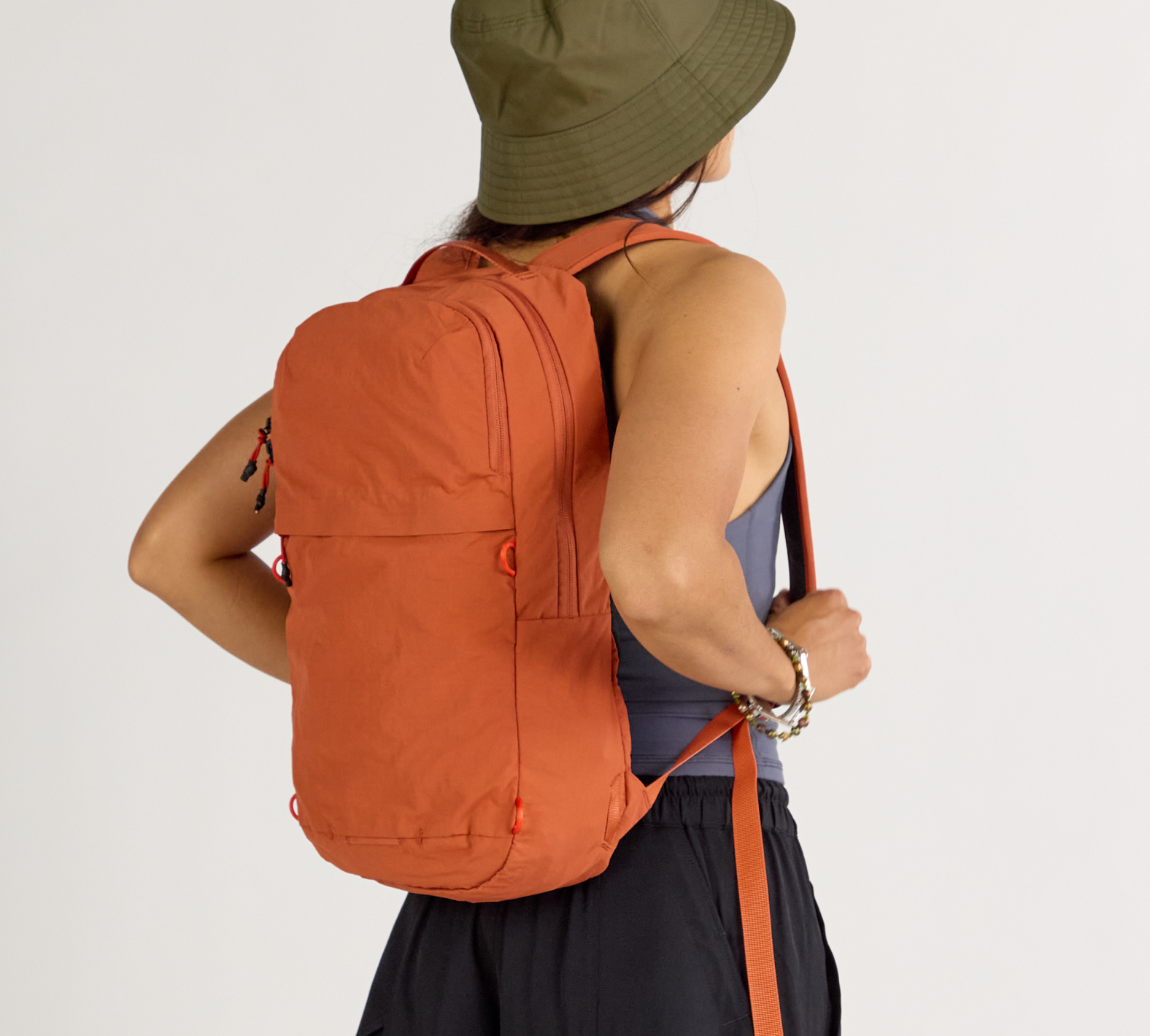 Back view of Stash Packable Backpack 16L in Sumac on model showing slim, packable profile and adjustable shoulder straps
