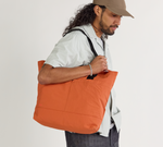 A model wearing the Stash tote in sumac.