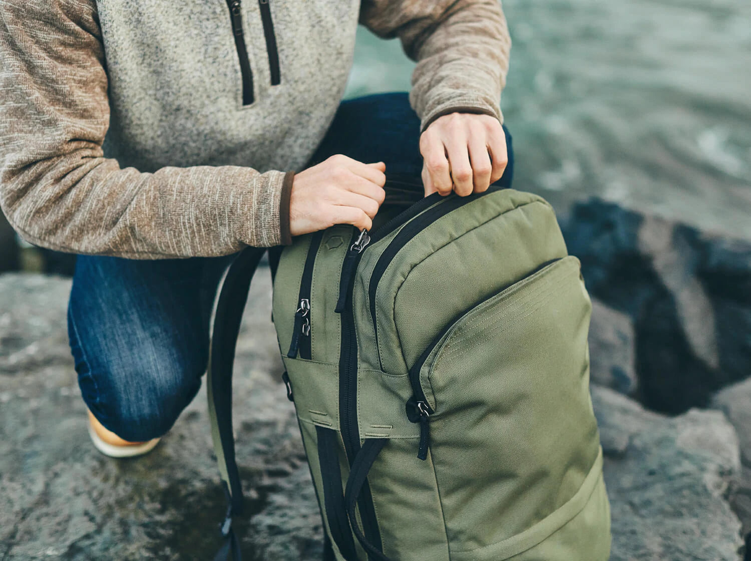 man opens the pakt travel backpack in green