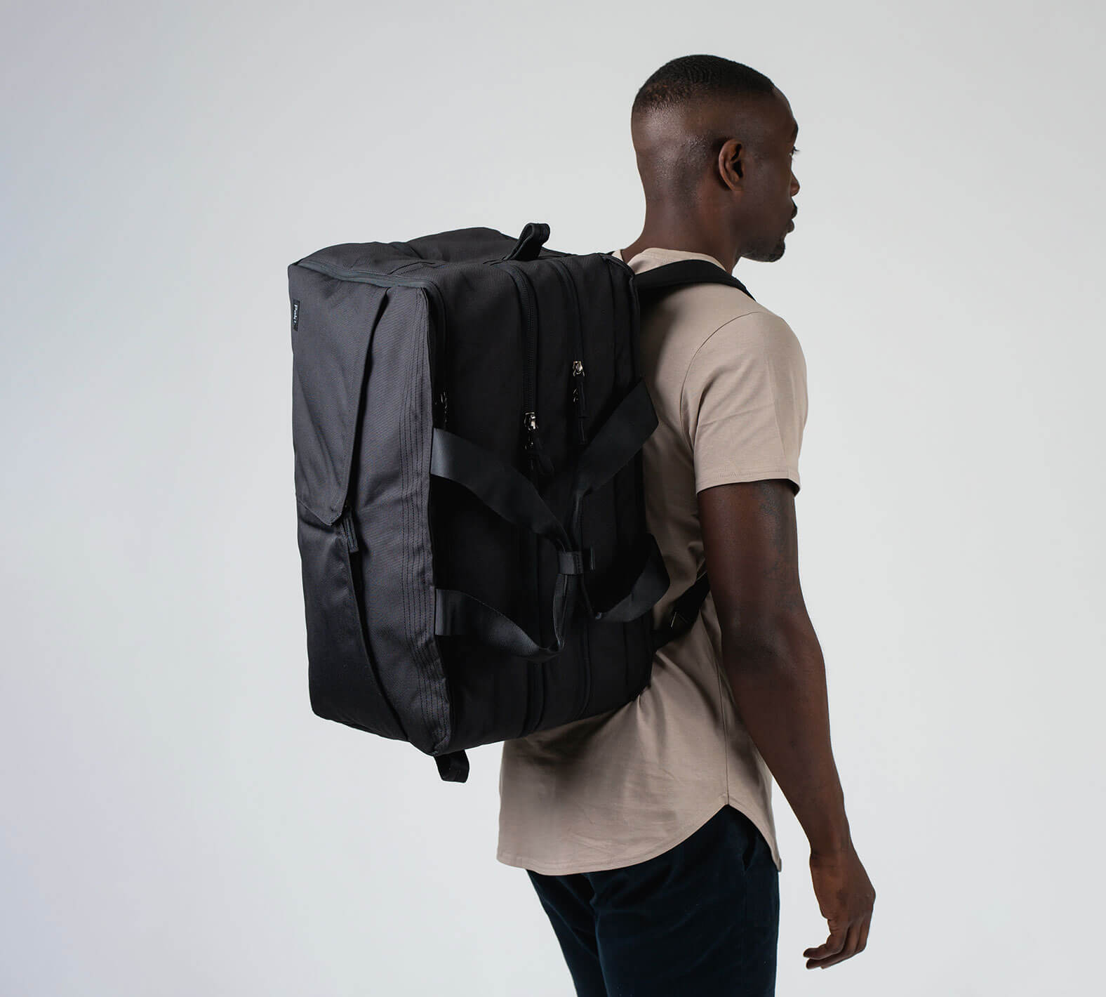 the 50L duffel/backpack in black on a male model, wearing it as a backpack