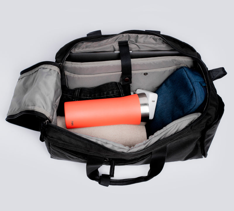 Open black duffel bag showing an orange water bottle, a rolled towel, and folded clothing in interior compartments.