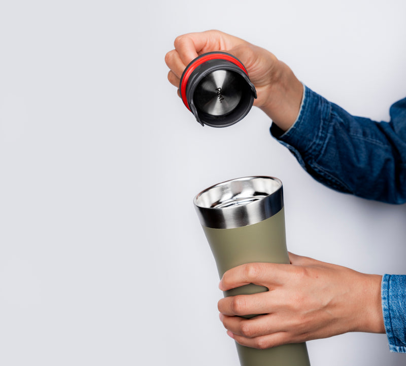 Two hands removing a lid from an insulated travel mug